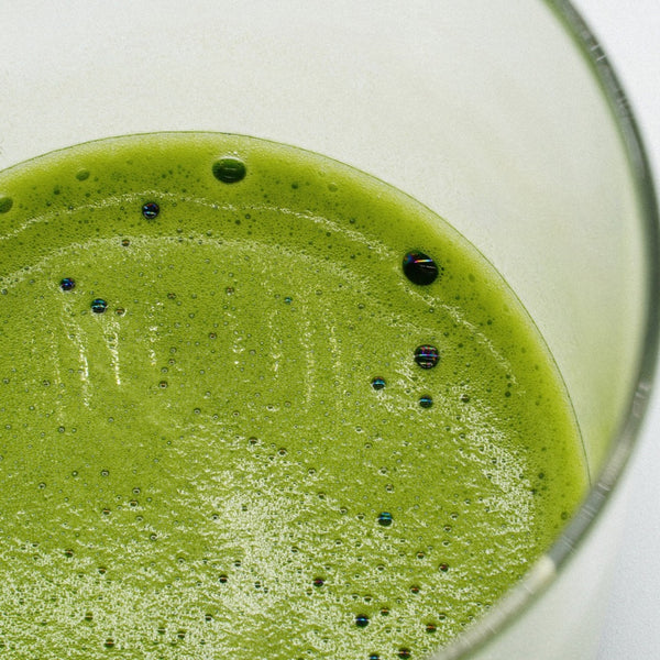 Išplakta premium matcha stiklinėje prieš pilant augalinį pieną